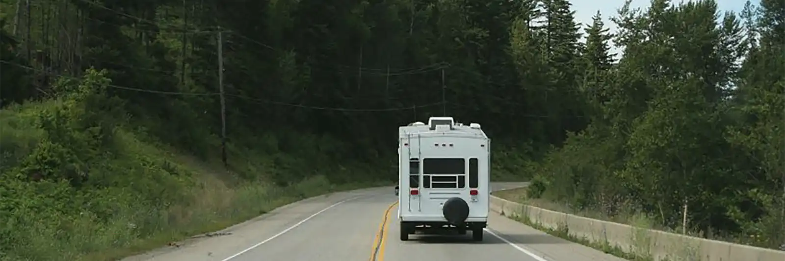 Fifth wheel towing down a road through the pines
